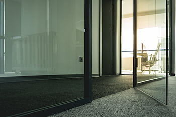 Contemporary office space with glass doors and minimalist design elements. HD wallpaper
