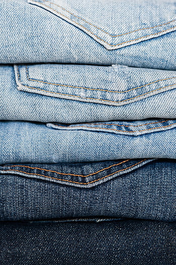 Close-up view of stacked denim jeans showcasing different shades and styles for fashion retail. HD phone wallpaper