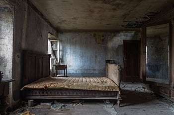 Explore the haunting beauty of an abandoned rustic bedroom, displaying decayed furniture and peeling walls. HD wallpaper