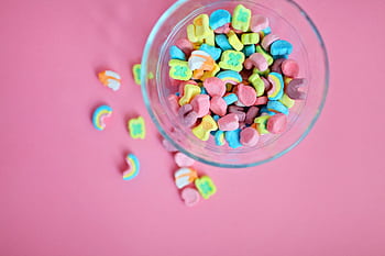 Bright and colorful marshmallow candies in a glass bowl on a pink backdrop, perfect for sweets lovers. HD wallpaper