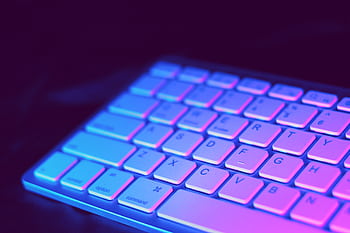 Close-up of a modern keyboard illuminated with vibrant purple and blue neon lighting. HD wallpaper