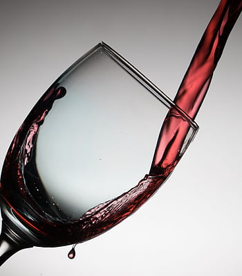 Dramatic capture of red wine being poured into a tilted glass, showcasing elegance and flow. HD phone wallpaper