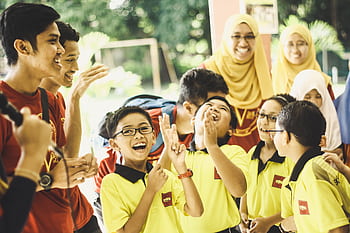 A group of school children enjoying a celebratory outdoor event with teachers in Pahang, Malaysia. HD wallpaper