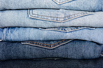 Close-up of folded denim jeans showcasing various shades and textures. HD wallpaper