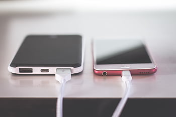 Two smarts charging side by side on a desk. Modern and technological setting. HD wallpaper