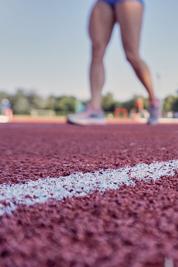Closeup view of athlete's legs standing on outdoor track, perfect for sports-related themes. HD phone wallpaper