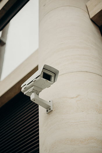 Close-up of a CCTV camera on a concrete building, symbolizing security and technology. HD phone wallpaper