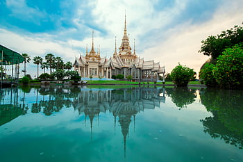 Beautiful Thai temple with serene reflection in water, showcasing spirituality and culture. HD wallpaper