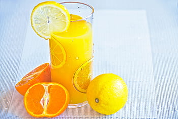 Vibrant citrus juice in a glass with fresh orange and lemon slices, offering a refreshing taste of summer. HD wallpaper