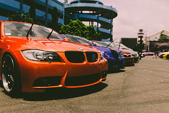 Close-up of vibrant sports cars parked outdoors, showcasing custom modifications and sleek designs. HD wallpaper