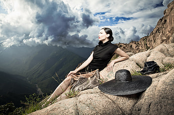 Take a rest, dreamer, thoughts, beauty, black dress, lady, sun, hat, bag, journey, beautiful, grass, rocks, mountain, rest, green, clouds, nature, sky, boots HD wallpaper