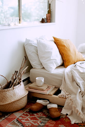 A cozy bedroom setup featuring pillows, a blanket, and warm-toned decor. HD phone wallpaper