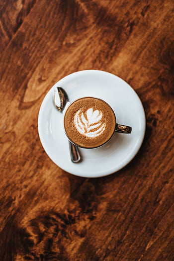 A top-down view of cappuccino with latte art, placed on a rustic wooden table. HD phone wallpaper