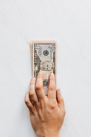 A hand holds a stack of US dollar bills, symbolizing wealth and finance. HD phone wallpaper