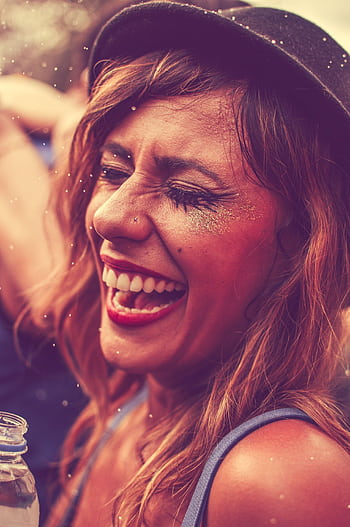 Smiling woman enjoying a fun nightclub party, wearing glitter and trendy hat. HD phone wallpaper