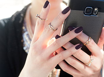 Close-up of a woman with manicured nails and rings holding a smart, showcasing fashion elegance. HD wallpaper
