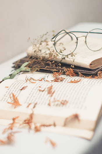 An open book with vintage eyeglasses surrounded by dried leaves, symbolizing knowledge and nostalgia. HD phone wallpaper