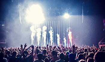 Vibrant concert scene with cheering crowd and bright stage lights creating an electric atmosphere. HD wallpaper