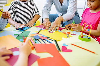 Group of diverse children enjoying creative art activities in a vibrant classroom setting. HD wallpaper