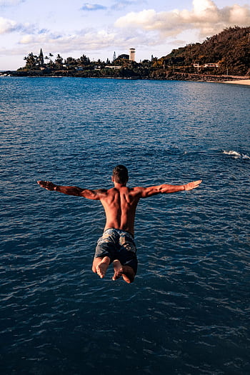 A shirtless man jumps into the ocean, symbolizing dom and adventure. HD phone wallpaper