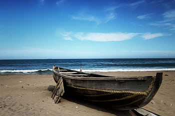 A serene scene of a rustic boat on the sandy shores of Visakhapatnam, India. HD wallpaper