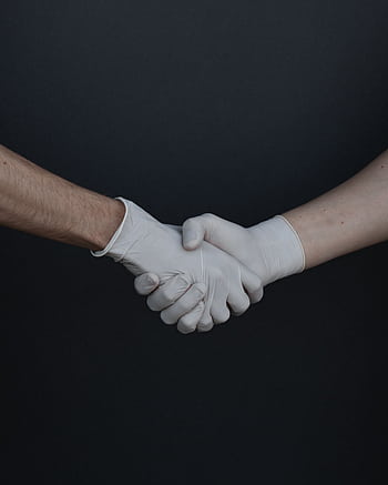 Two people shaking hands while wearing latex gloves, illustrating safety and protection. HD phone wallpaper