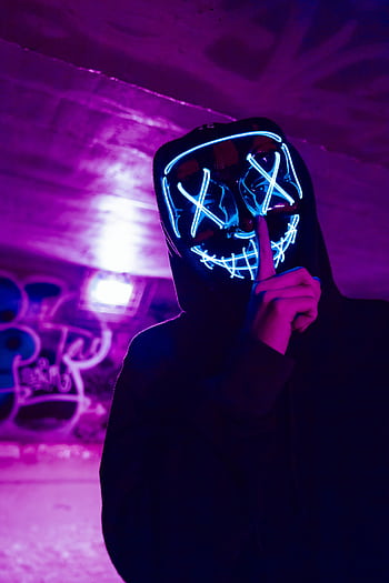 Eerie figure wearing a neon LED mask in a dimly lit urban environment, creating a mysterious atmosphere. HD phone wallpaper