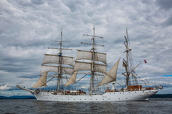 A stunning view of a classic sailing ship navigating the waters of Hol, Norway, under a dramatic sky. HD wallpaper