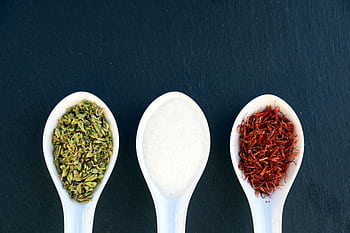 Three ceramic spoons with herbs, salt, and saffron on dark slate background. HD wallpaper