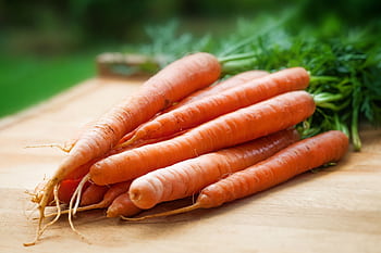 A bunch of fresh organic carrots on a wooden surface, perfect for healthy cooking. HD wallpaper
