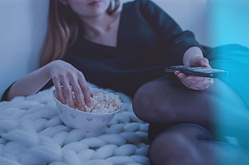 Cozy evening scene with woman enjoying popcorn and watching TV. HD wallpaper
