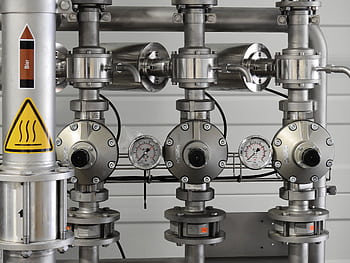 Close-up of stainless steel pipes with pressure gauges in an industrial setting. HD wallpaper