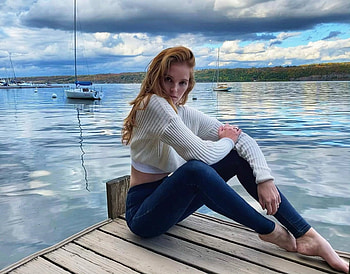 Alexina Graham, boat dock, sitting, bare feet, redhair, white sweater, green eyes, skin tight jeans, jewelry, lake, sailing boats HD wallpaper