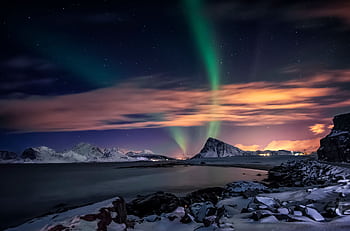 Breathtaking view of the Northern Lights illuminating the snowy Nordland coastline in Norway at night. HD wallpaper