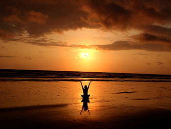 Peaceful meditation silhouette at sunset on a serene beach. HD wallpaper