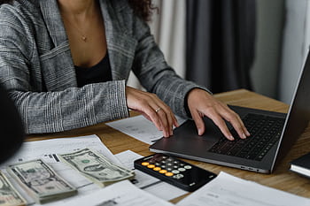 A businesswoman working on finance management with cash and calculator on desk. HD wallpaper