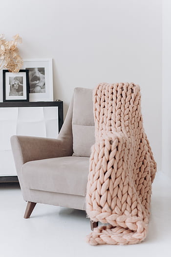 A modern beige armchair draped with a knitted throw blanket in a cozy interior setting. HD phone wallpaper