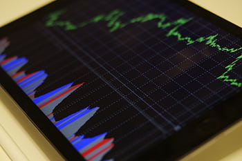 Close-up of a tablet displaying stock market analysis with colorful graphs. HD wallpaper