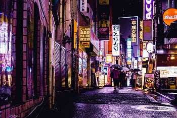 Colorful neon lights illuminate a bustling Tokyo street at night, with reflections on wet pavement. HD wallpaper