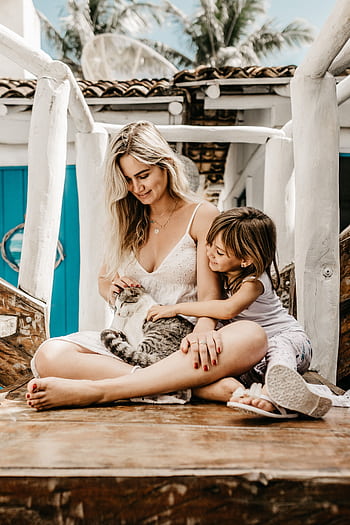 A joyful moment between a mother, daughter, and their pet cat on a sunny day outdoors. HD phone wallpaper