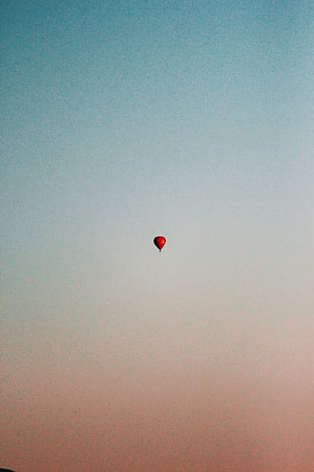 A solitary hot air balloon ascends in a tranquil sky at sunset, offering a serene and minimalistic view. HD phone wallpaper