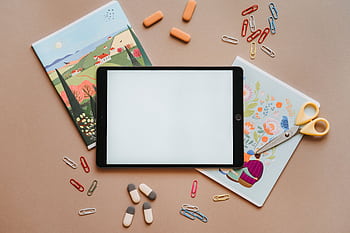 Flat lay of colorful stationery with tablet, notebooks, and scissors, ideal for education themes. HD wallpaper