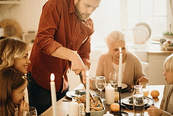 A warm family gathering around a festive Thanksgiving dinner table with candles and smiles. HD wallpaper