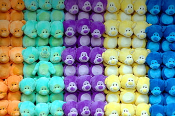 Vibrant pastel teddy bears in a colorful pattern at a carnival game stall wall display. HD wallpaper