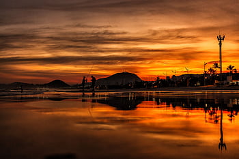 Silhouetted fishermen at sunset on a serene lake with reflections and mountains. HD wallpaper