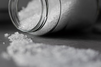 Detailed of rock salt pouring out from a glass jar with a selective focus effect. HD wallpaper