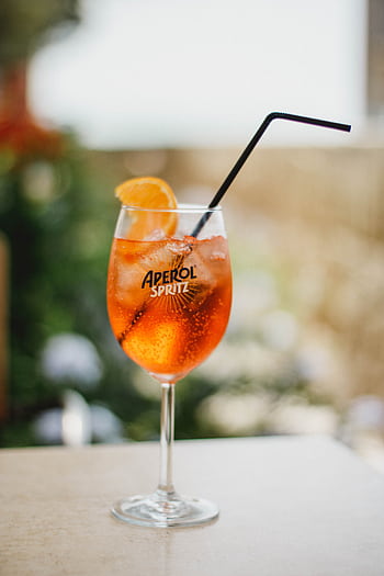 A close-up of a refreshing Aperol Spritz cocktail with ice and orange slice. HD phone wallpaper