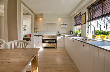 Bright kitchen interior featuring wooden flooring, sleek cabinets, and natural sunlight. HD wallpaper
