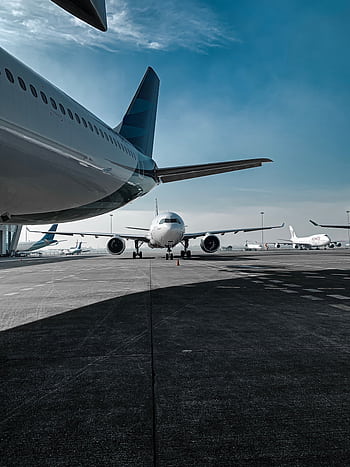 Multiple airplanes parked on the airport runway under a clear sky, ready for departure. HD phone wallpaper