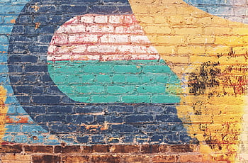 Vibrant street art featuring abstract designs on a rustic brick wall, showcasing urban creativity. HD wallpaper